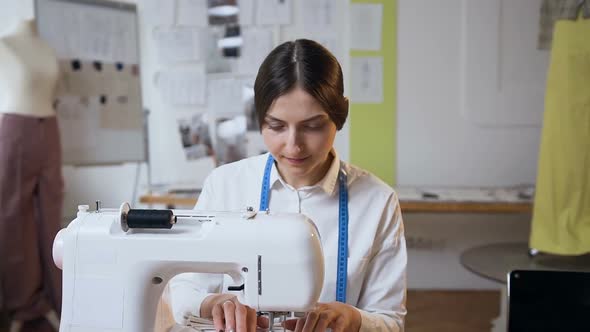 Young Female Tailor Working on Sewing Machine in the Sew Studio