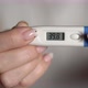Woman Holds Thermometer in Hands to Measure Body Temperature - VideoHive Item for Sale