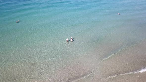 Turquoise clear water, light waves and free beach. People swim in small groups.