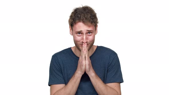 Portrait of Nervous European Guy in Tshirt Posing with Praying Hands and Worrying with Fright or