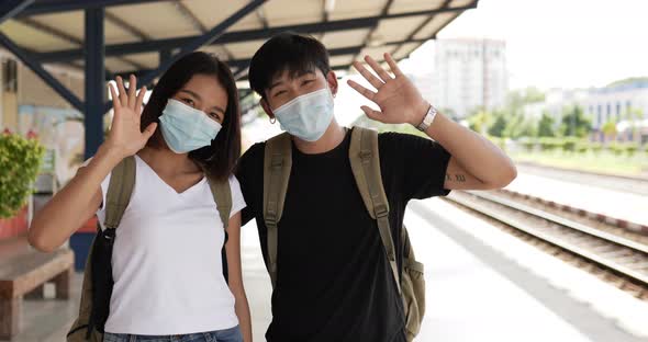 Couple waving hand and looking at camera stand in train station