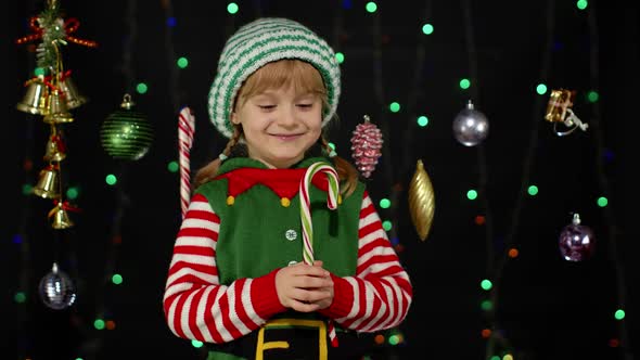 Kid Girl in Christmas Elf Santa Helper Costume Receiving Lollipop Gift Candy Cane
