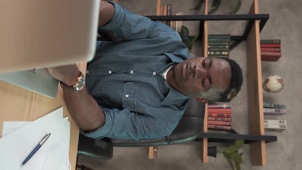 Vertical. Smiling African Man Employee Works in the Office at the Computer. Black Businessman