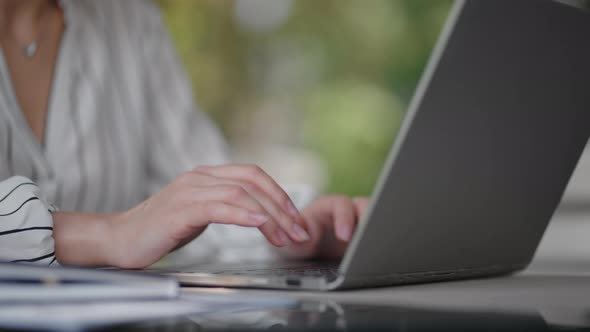 Closeup of a Woman Typing on a Laptop Keyboard While Sitting in a Summer Cafe