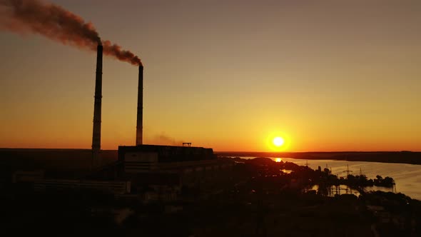 Dark factory against the orange setting sun