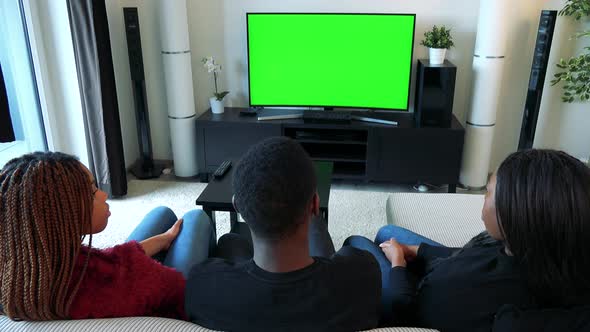 Three African Friends Watch Television in Living Room and Talk About Something - Green Screen