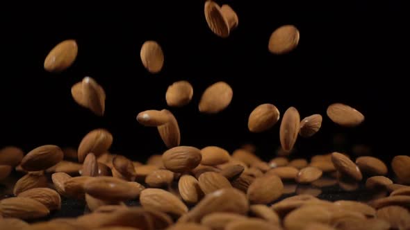 Almonds Fall Onto a Hard Black Surface