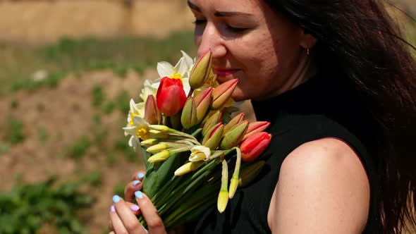 Beautiful young woman holding a bouquet of spring wildflowers in her hands.