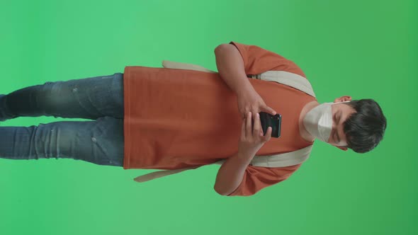 Asian Boy Student Wearing A Mask, Using Mobile Phone While Walking  To School On Green Screen