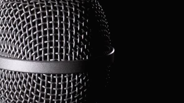 The Microphone Rotates on a Black Background. Dynamic Microphone Grid Spins Close-up