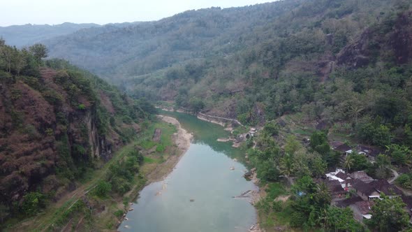 Beautiful aerial view of a river in the middle of the mountains in the morning with village housing