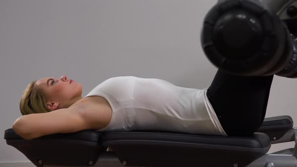 A Young Beautiful Woman Does Crunches on a Bench in a Gym - Closeup From the Side