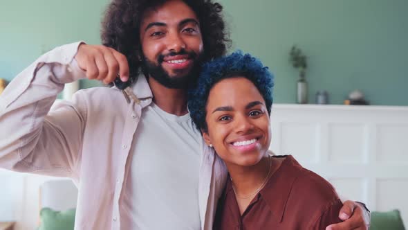 Young Multiracial Family Smile Demonstrate Keys to House Stands in Living Room