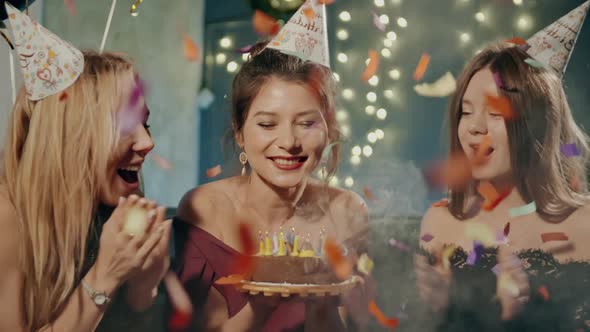 Portrait of Attractive Asian Girl Blowing Out Fire Candles on Birthday Cake Under Falling Glowing