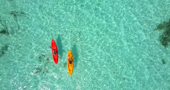 Aerial drone view of a man and woman couple kayaking around a tropical island