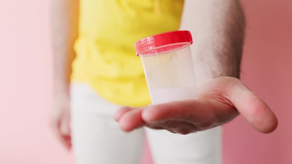 Close up of defocused man zipping up his fly, gives the doctor a plastic jar with a sample of sperm