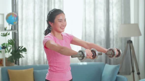 Asian Athletic Girl In Leggings And Top Crouches With Dumbbells At Home. Sport, Healthy Lifestyle