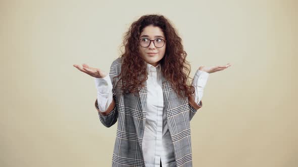 The Young Woman with a Wide Smile Puzzled with Curly Hair in a Gray Jacket and White Shirt with