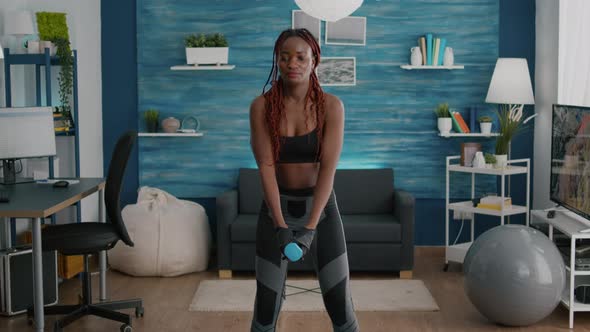 Flexible Woman with Dark Skin Doing Squat Exercise Using Dumbbells