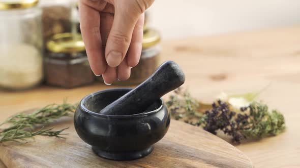 Woman's Hand Puts Herbs and Flowers Into the Granite Mortar with Pestle