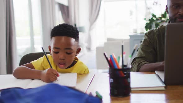 African american father and son doing homework and using a laptop together