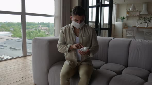 A man in a protective mask in the apartment is studying the composition of the disinfectant
