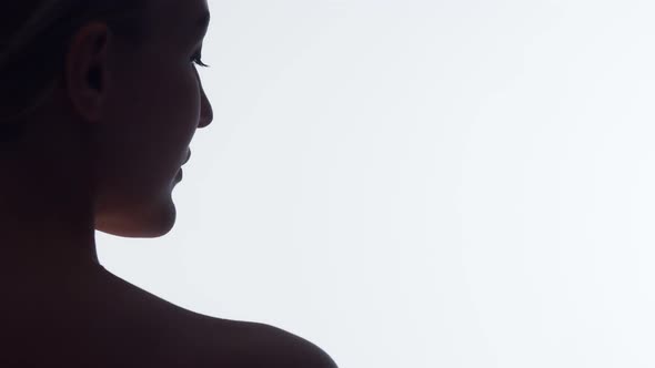 Closeup silhouette nape of woman on white background in studio, turns head to side showing beautiful