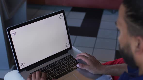 Happy mixed race man sitting in cafe using a laptop