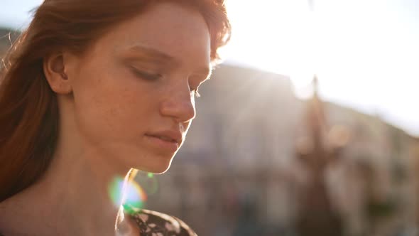 Dreamy Young Ginger Girl Looking Away Than Down and in Camera with Solar Flare in Slowmotion