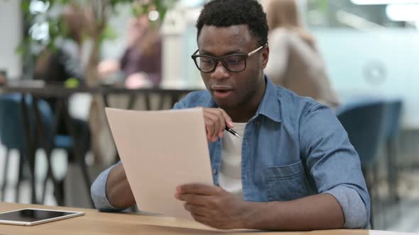 Young African Man Celebrating While Reading Documents