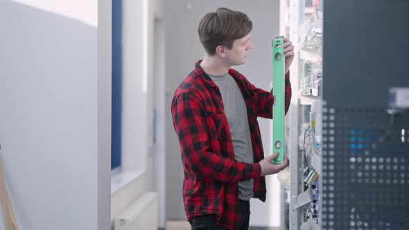 Young Brunette Man Choosing Level Ruler in Hardware Store