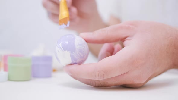 Men's Hands are Painting an Easter Egg with a Brush