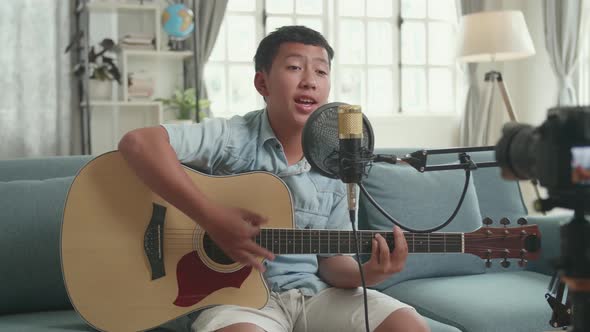 Asian Boy Playing Guitar And Sing A Song. The Boy Is Streaming