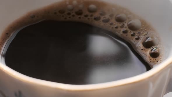 Hot Black Coffee Steaming with Bubbles in Coffee Cup