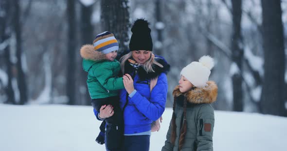 Young Mother Carries Her Little Son in Her Arms in Winter