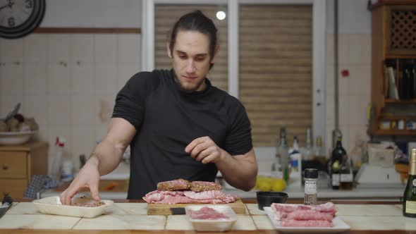 Young Caucasian Man Looks Happy While Taking Burgers Out of the Tray for Preparation in Slow Motion