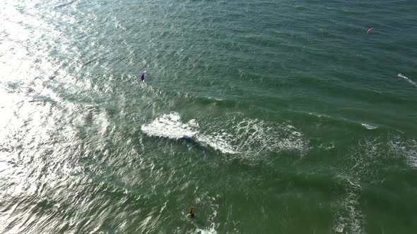 AERIAL: Locked Shot of Surfers in Green Baltic Sea on  Sunny Bright Day in Natural Daylight