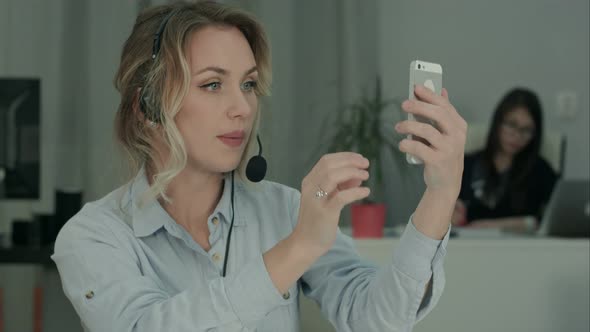 Young Office Worker in Headset Taking Selfies on Her Phone