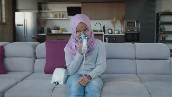 Lovely Sick Islamic School Age Girl Wearing Mask Nebulizer Inhaling Vapor Sprayed Medication Indoor