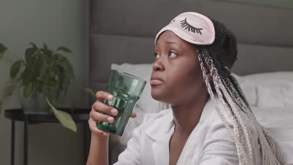 Thoughtful Black Woman Drinking Glass of Water in Morning