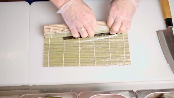 Male Hands in Gloves Cooking Sushi Rolls in a Restaurant Kitchen Close Up