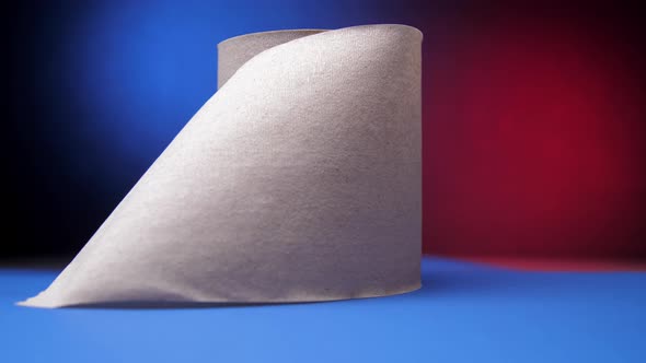 Grey Roll of Toilet Paper on Table Against Blue and Red