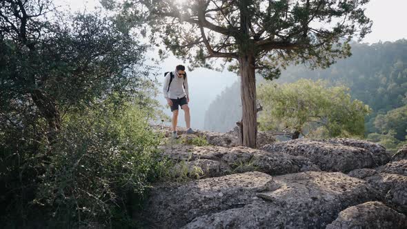 Guy Traveler Walks Over the Stones on the Mountain Around the Trees