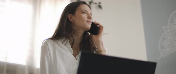 Close up of a woman in white shirt talking to someone on the phone