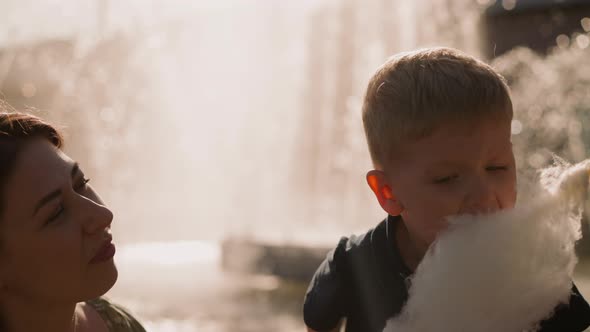 Mother Looks at Son Biting Cotton Candy with Sister in Park