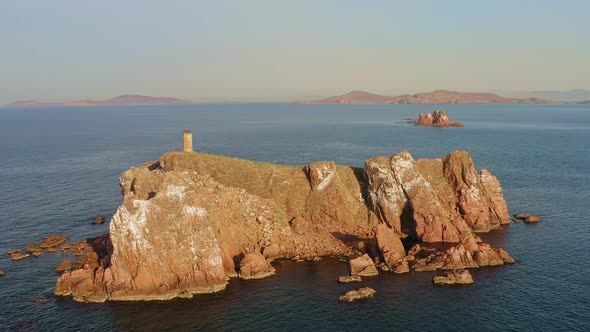 An Abandoned Lighthouse on Top of a Rocky Island at Sunrise