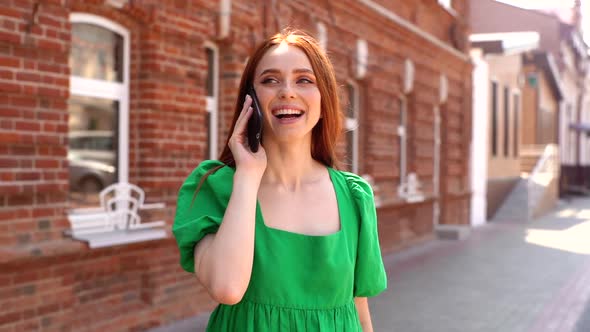 Portrait of Happy Charming Young Woman Talking on Mobile Phone Standing on City Street in Sunny