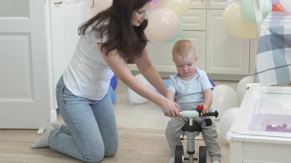 Mother and Baby Boy Play on the Floor Mother Teaches 1 Year Old Child to Ride a Balance Bike