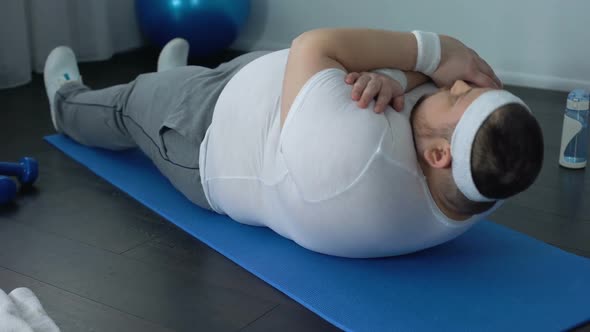 Fat Man Hardly Doing Sit-Ups on Mat at Home, Obesity Difficulties, Weak Muscles