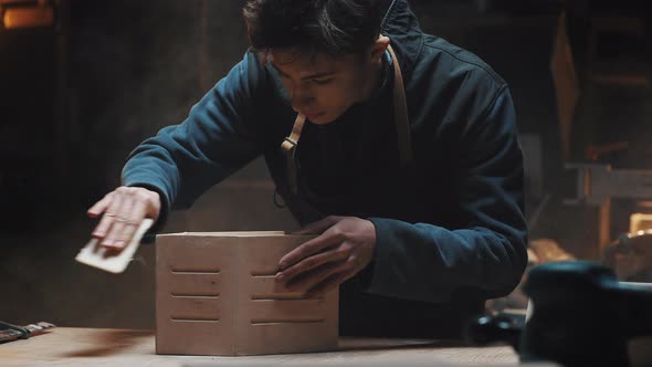 Portrait of a Young Attractive Caucasian Master Carpenter Polishing a Wooden Birdhouse
